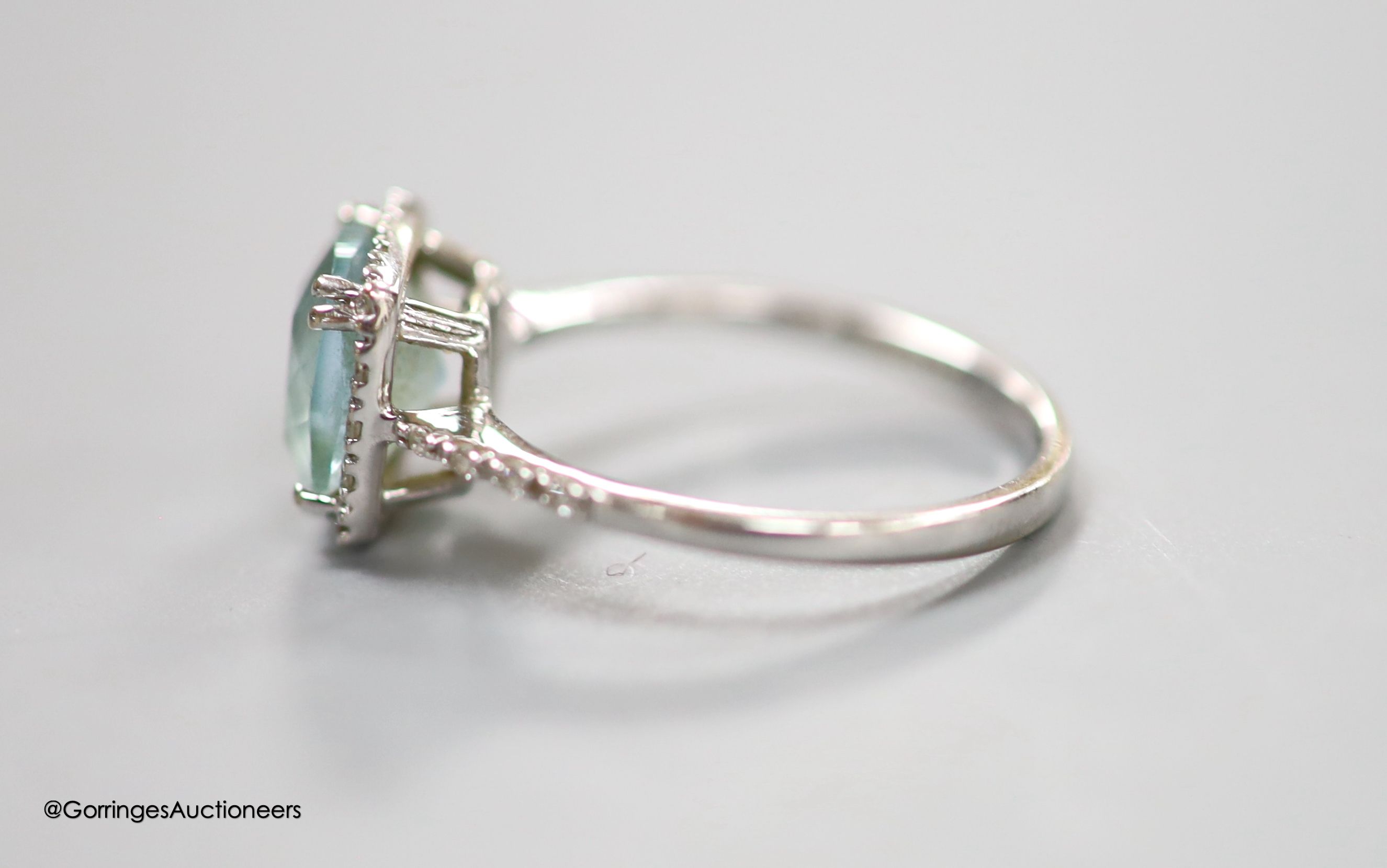 A modern 18ct white gold, blue topaz and diamond chip set square cluster ring, with diamond chip set shoulders, size M, gross 2.9 grams.
